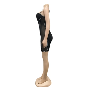 Detail of black bodycon mini dress with sheer mesh side panels and white pearl trim