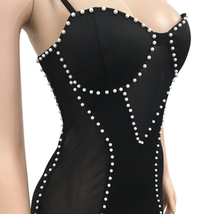Detail of black corset dress featuring white pearl trim and sheer mesh side panels