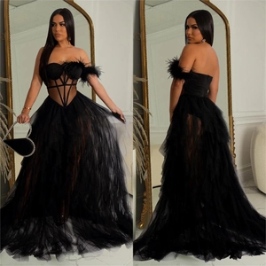 Detail view of black strapless evening gown with feather cuffs and tiered tulle skirt