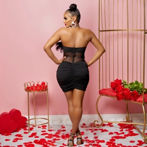 Detailed back view of a black ruched mini dress with sexy sheer mesh paneling