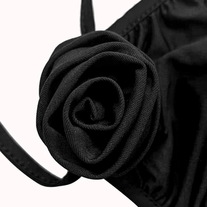 Detailed close-up of a decorative 3D fabric rose on a black elastic ribbed dress