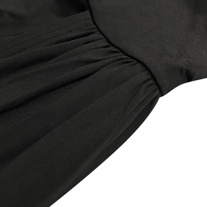 Detailed macro view showing the pleated fabric and precise stitching of the black dress