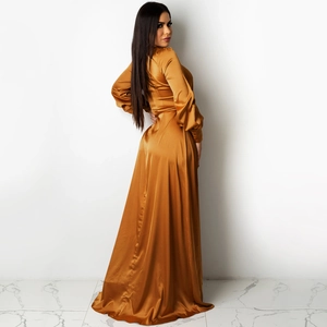 Détail de la robe longue en satin doré avec manches longues et ourlet évasé élégant