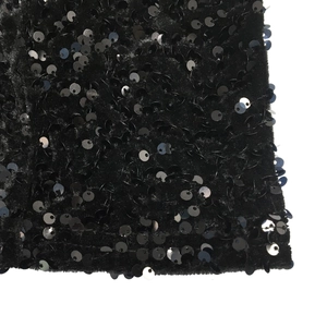 Close-up of black sequins sewn on soft velvet fabric showing texture and reflective shine