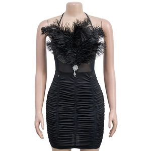 Detailed view of black party dress featuring soft feathers, ruched fabric, and rhinestones