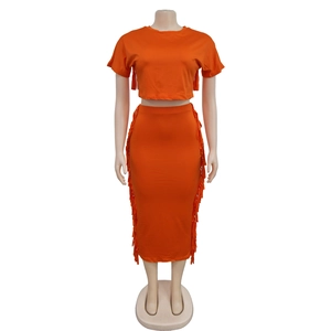 Détail d'un ensemble orange deux pièces avec franges sur le haut et la jupe midi