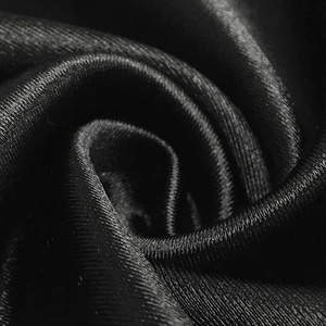 Macro shot of high-quality black satin fabric showing silky texture and smooth drape