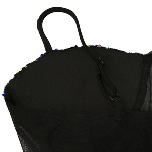 Détail d'une robe noire avec paillettes colorées, empiècements en résille et bretelles