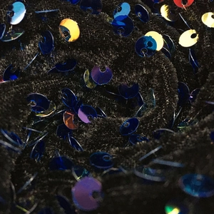 Gros plan de sequins bleus et dorés scintillants cousus sur un tissu en maille noire
