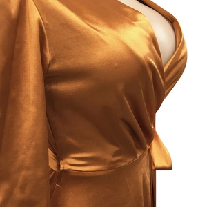 Détail de la robe portefeuille en satin doré avec ceinture élégante et éclat soyeux