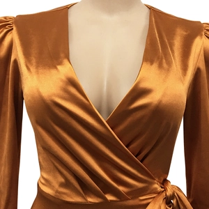 Détail d'une robe cache-cœur en satin bronze avec décolleté en V et manches bouffantes