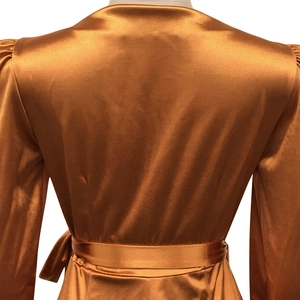 Détail du dos d'une robe cache-cœur en satin bronze avec ceinture et texture soie