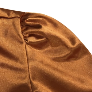 Détail de l'épaule en satin doré cuivré avec coutures froncées pour manche bouffante
