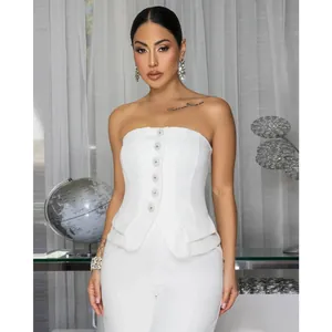 Detail of white strapless peplum top with decorative pearl buttons and tailored trousers