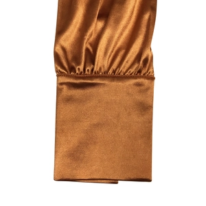 Détail des poignets froncés sur une robe en satin bronze avec des coutures de qualité
