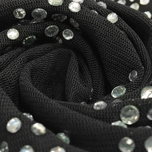 Dettaglio macro del tessuto a rete nero con strass scintillanti per abiti eleganti