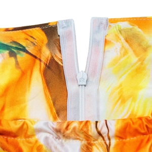 Detail of invisible white zipper with KYC engraving on vibrant floral long dress fabric
