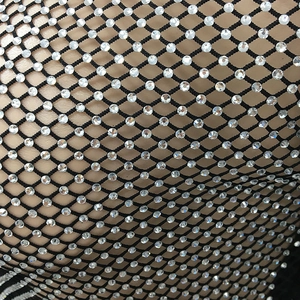 Makro-Detail glitzernder Strasssteine auf schwarzem Netzstoff für sexy Paillettenkleider