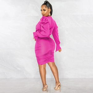 Détail de la texture froncée et manches bouffantes sur robe fuchsia à col en V