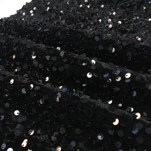 Makroaufnahme von schwarzen Pailletten auf Stoff mit Lichtreflexion und Texturdetails