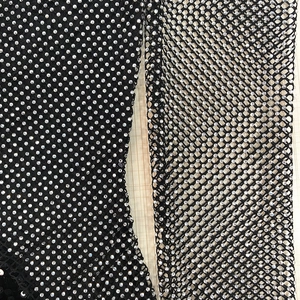 Detail von schwarzem Netzstoff mit silbernen Strasssteinen auf einem Kleid
