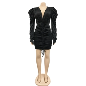 Détail de robe noire col en V avec fronces centrales, manches bouffantes et liens de serrage