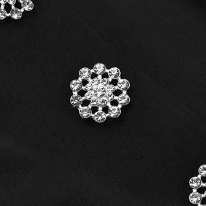 Detailed close-up of sparkling flower rhinestone button on black textured fabric