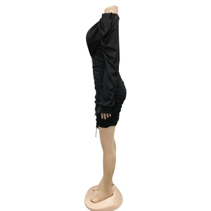 Détail de la robe noire à manches longues avec fronces latérales et coupe ajustée élégante