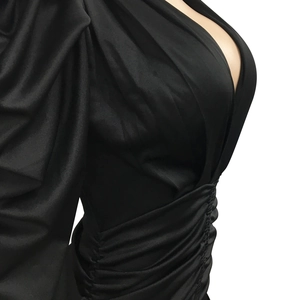 Détail d'une robe élégante en satin noir avec décolleté en V, taille froncée et manches bouffantes