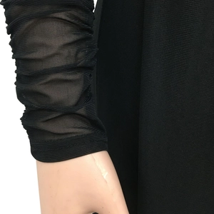 Detail of sheer black mesh sleeves with elegant ruched stacked texture on jumpsuit