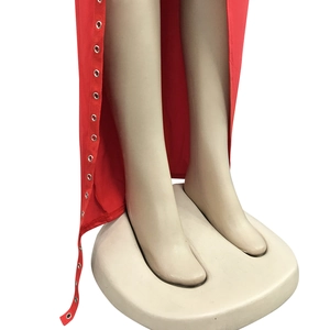 Détail d'une robe rouge à fente avec œillets métalliques argentés et tissu extensible