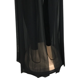 Detailed view of semi-transparent black mesh fabric with light draping and slit hemline