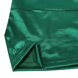 Detailed close-up of emerald green satin fabric with double-stitched reinforced hem