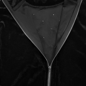 Close-up of V-neck zipper and silver rhinestone details on black velvet fabric