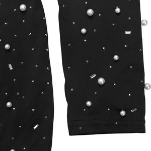 Détail de robe à col montant montrant des perles blanches et strass sur tissu noir