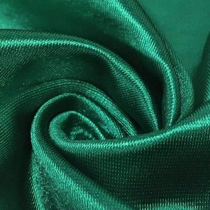 Macro shot of high-gloss emerald green satin fabric with fine twill texture and silky sheen