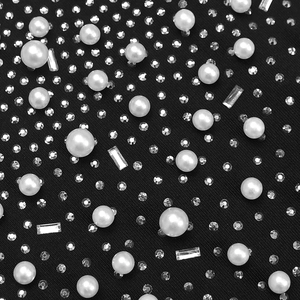Détail du tissu noir élégant orné de perles blanches et de strass brillants de luxe