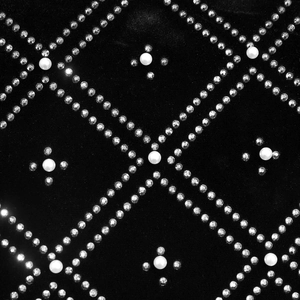 Detail view of black velvet fabric with rhinestones and pearls in a diamond pattern