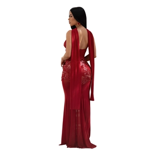 Detail view of a sequined red formal gown with flowing satin ribbons and sheer mesh hemline