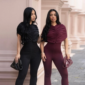 Detail of elegant slim-fit jumpsuits with draped neckline and flared leg in black and burgundy