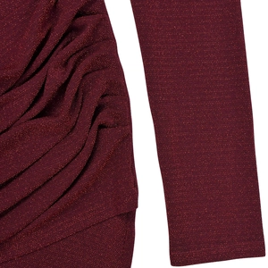 Detail of burgundy long sleeve dress featuring sparkling fabric and ruched side texture