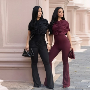 Detail view of ruched off-shoulder jumpsuits in black and wine red with flared pants