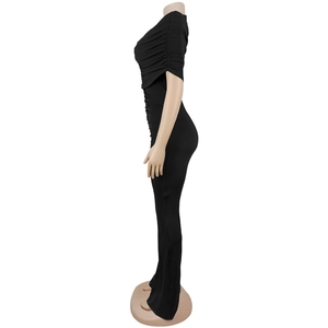 Detail view of side profile showing slim fit black jumpsuit with textured pleats