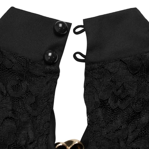 Detail shot of black lace dress showing neckline closure with two glossy buttons and floral mesh