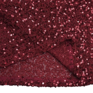 Détail macro du tissu à paillettes bordeaux avec couture professionnelle sur base tulle