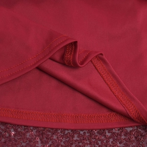 Détail d'une robe rouge montrant la double couture et l'ourlet en dentelle à paillettes