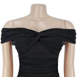 Detail of black off-shoulder mesh dress featuring twisted knot and ruched texture