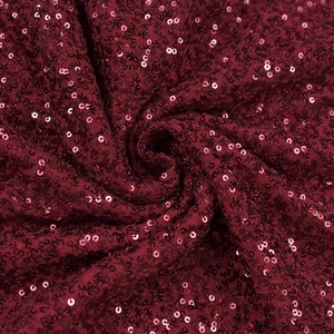 Détail du tissu à paillettes bordeaux chatoyant avec un drapé en spirale très élégant