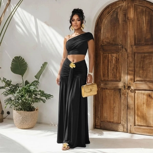 Ensemble chic noir deux pièces avec crop top asymétrique et jupe longue froncée à boucle dorée