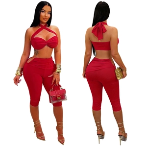 Detail of red halter cross-over crop top and high-waisted cut-out side trousers set